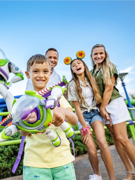 Kid with Buzz Lightyear toy in front of Buzz Lightyear statue at Walt Disney World Resort, Orlando.