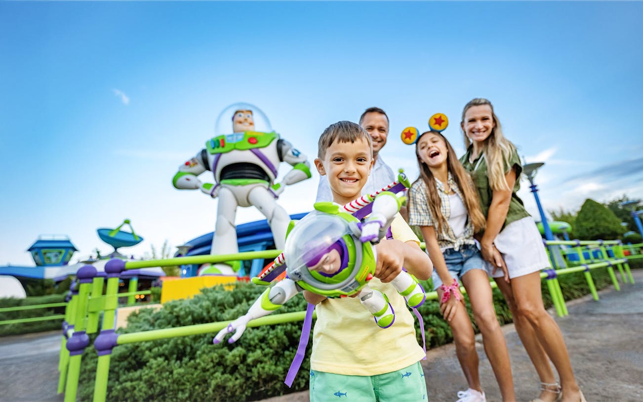 Kid with Buzz Lightyear toy in front of Buzz Lightyear statue at Walt Disney World Resort, Orlando.