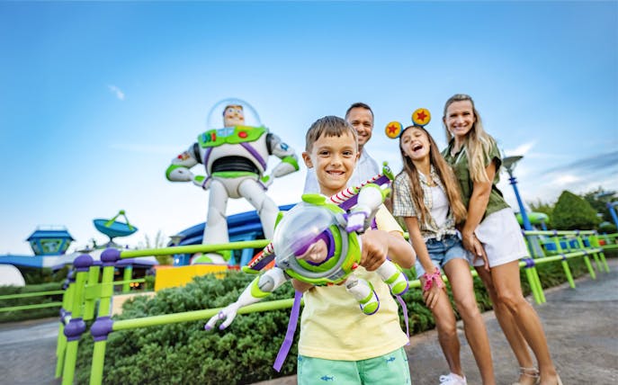 Kid with Buzz Lightyear toy in front of Buzz Lightyear statue at Walt Disney World Resort, Orlando.