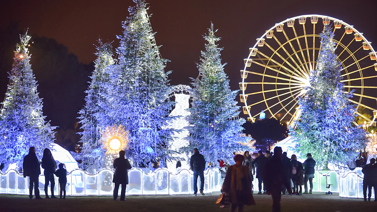 Christmas market in Nice with illuminated trees and Ferris wheel at night.