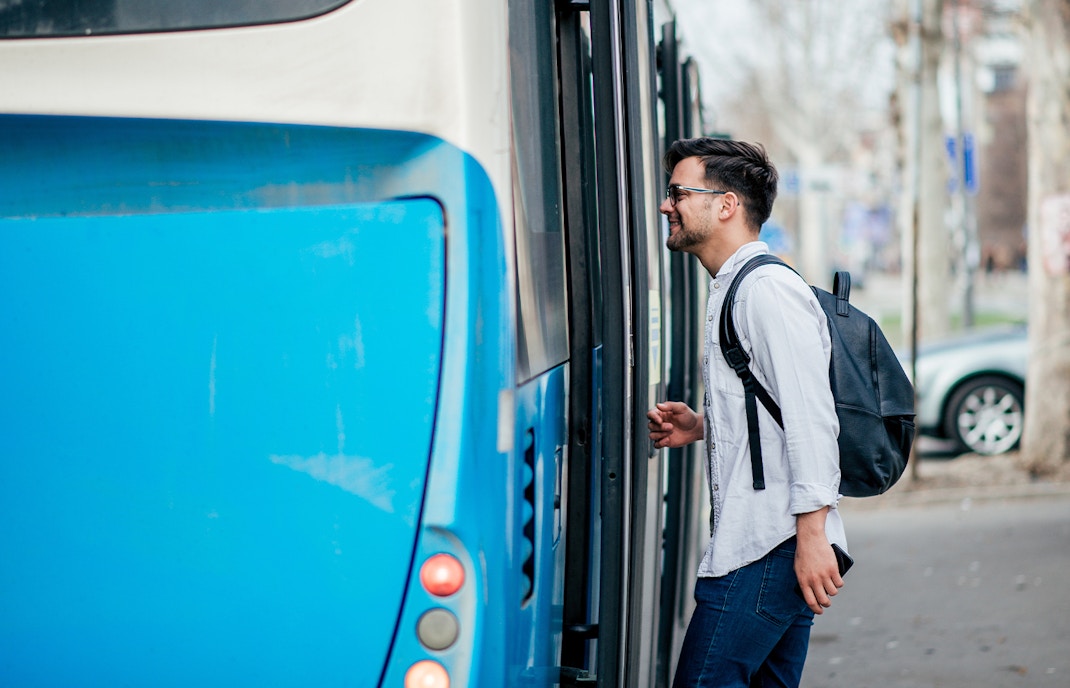 Man boarding onto a blue bus