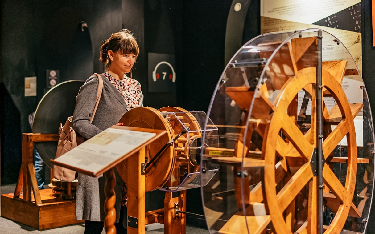Visitor observing Leonardo da Vinci's machine model at the Leonardo Interactive Museum.
