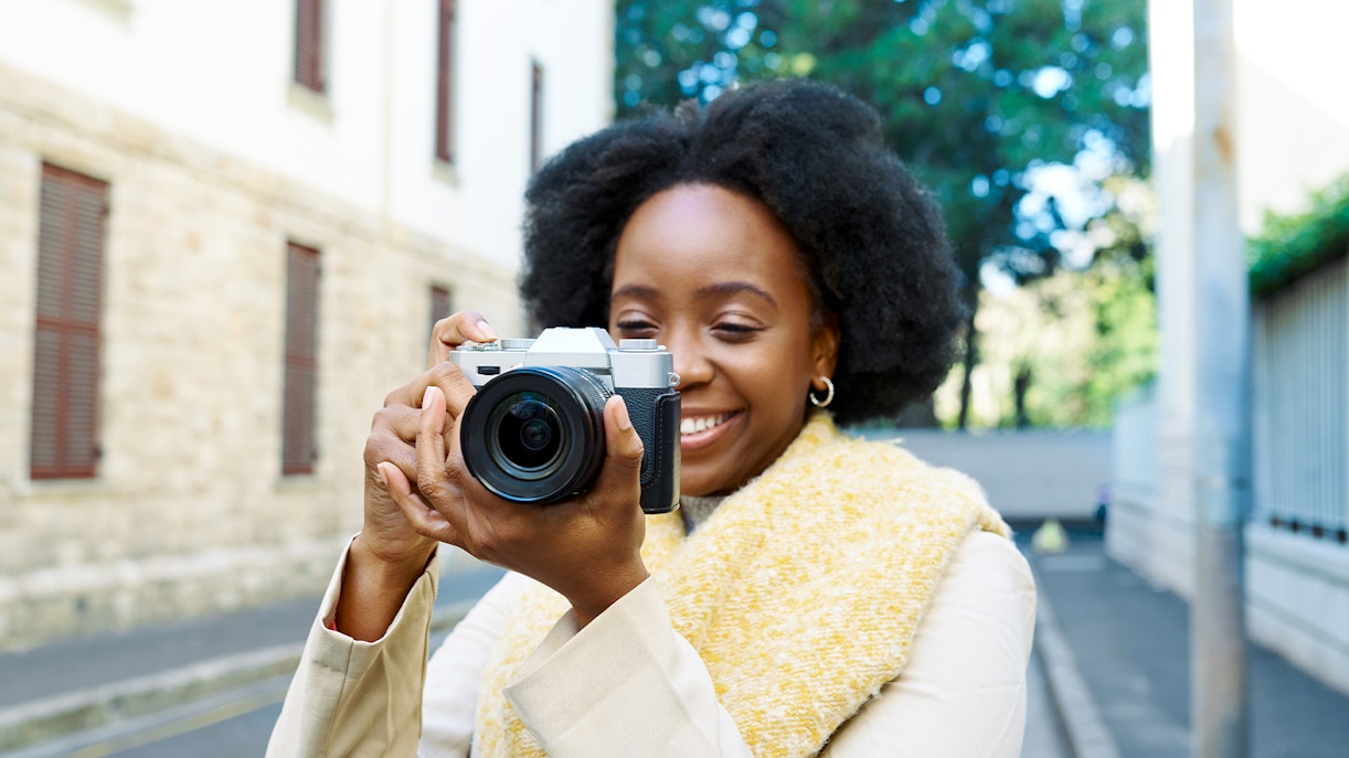 Woman taking photos with a camera on a city street.