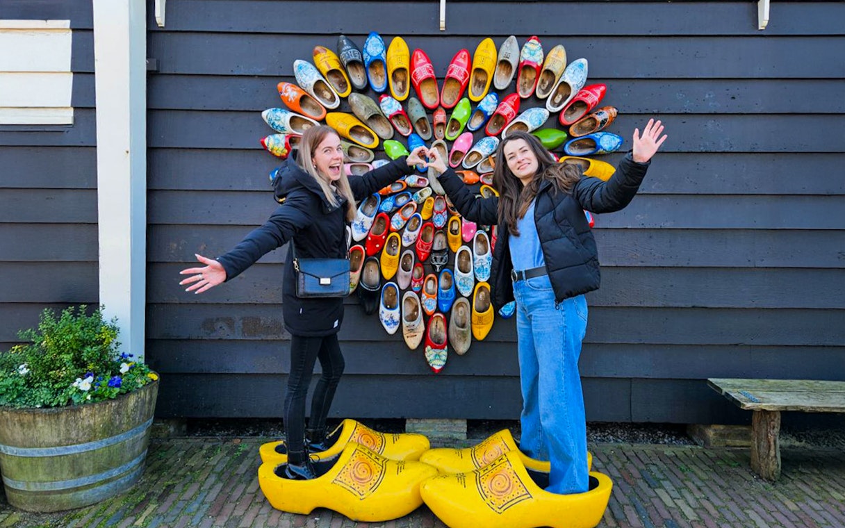 Guests posing with colorful clogs at Zaanse Schans, Netherlands.