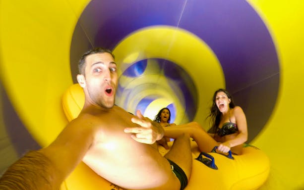 People enjoying a water slide at Therme Erding's Tropical Spa entrance.
