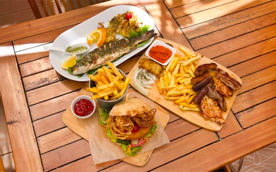 Snacks served during Elaphite Islands Cruise tour by Karaka, featuring grilled fish, fries, and a burger.