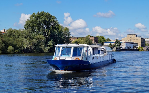 Cruise boat on the Spree River in Berlin with cityscape in the background.