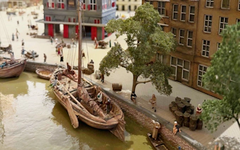 Historic canal scene with boats and people near a brick building at the dam.