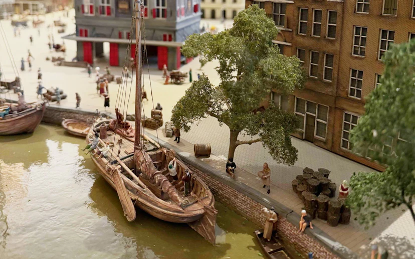 Historic canal scene with boats and people near a brick building at the dam.
