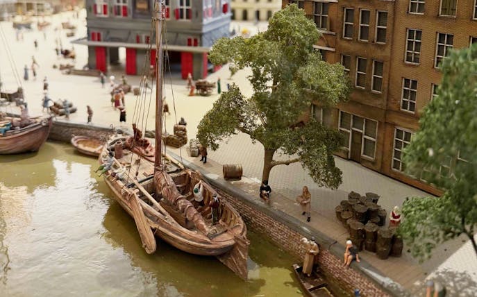Historic canal scene with boats and people near a brick building at the dam.
