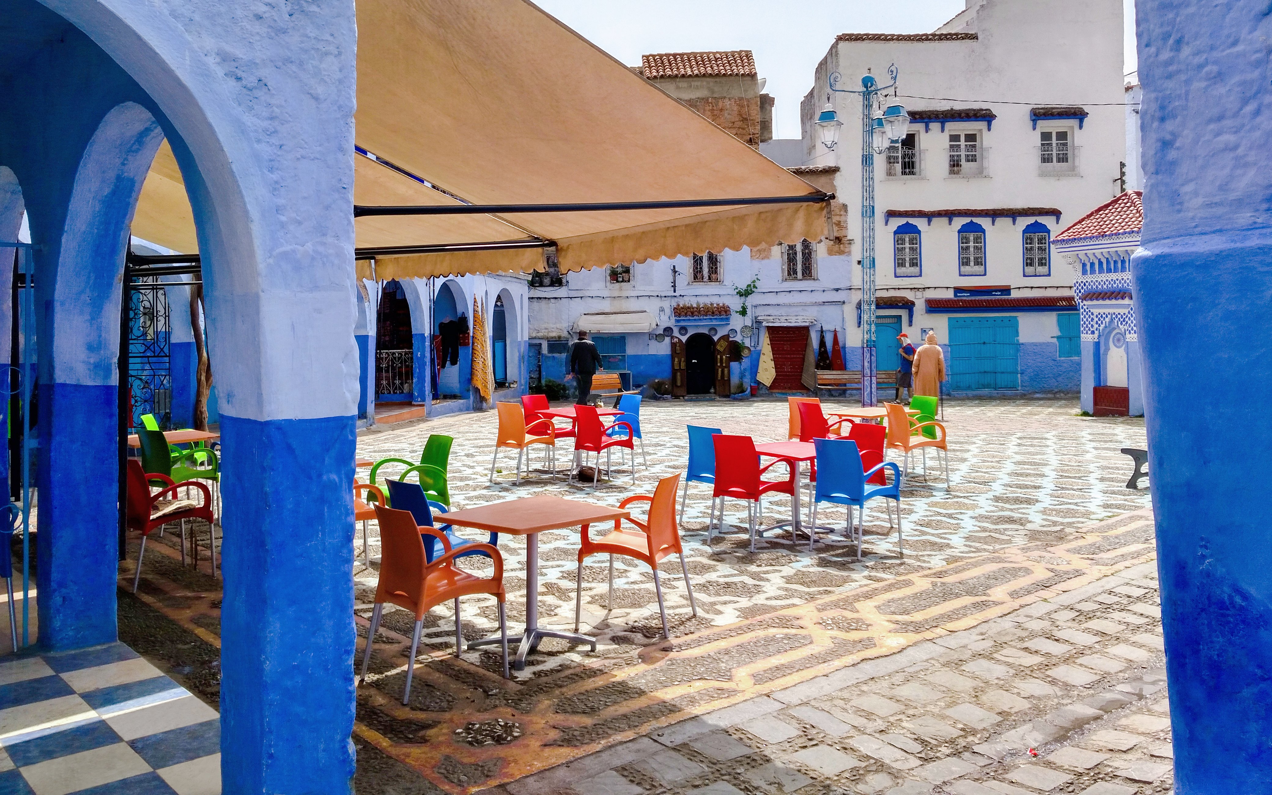 Colorful chairs in a courtyard surrounded by blue buildings in Chefchaouen, Morocco.