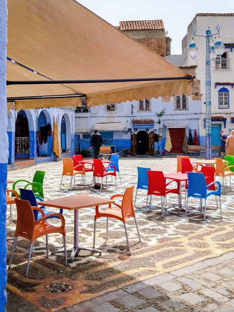 Colorful chairs in a courtyard surrounded by blue buildings in Chefchaouen, Morocco.