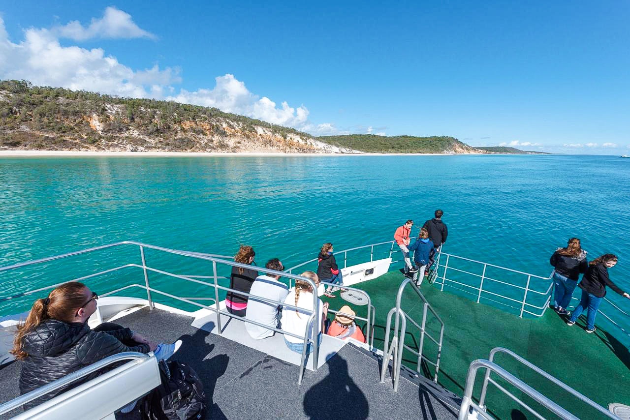 Guests on a boat deck view Fraser Island shoreline from Hervey Bay.
