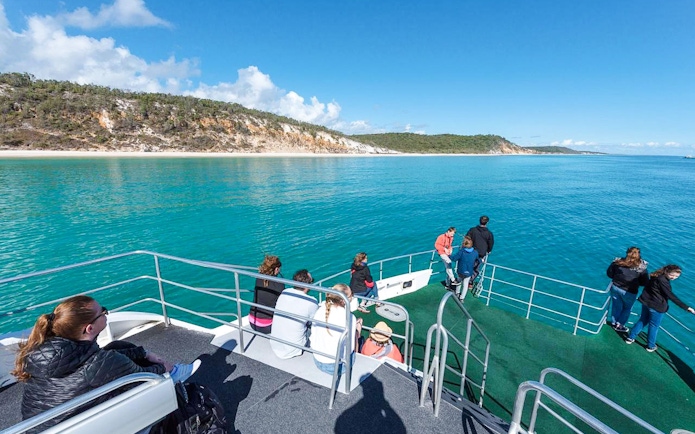 Guests on a boat deck view Fraser Island shoreline from Hervey Bay.