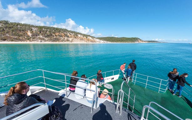 Guests on a boat deck view Fraser Island shoreline from Hervey Bay.