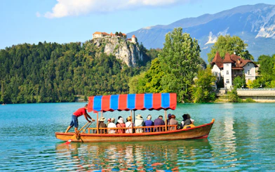 Tourists on a boat ride at Bled Lake with Bled Castle in the background.