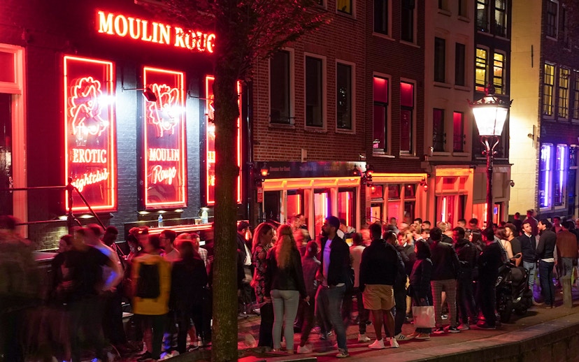 Crowd outside Moulin Rouge in Amsterdam's Red Light District at night.