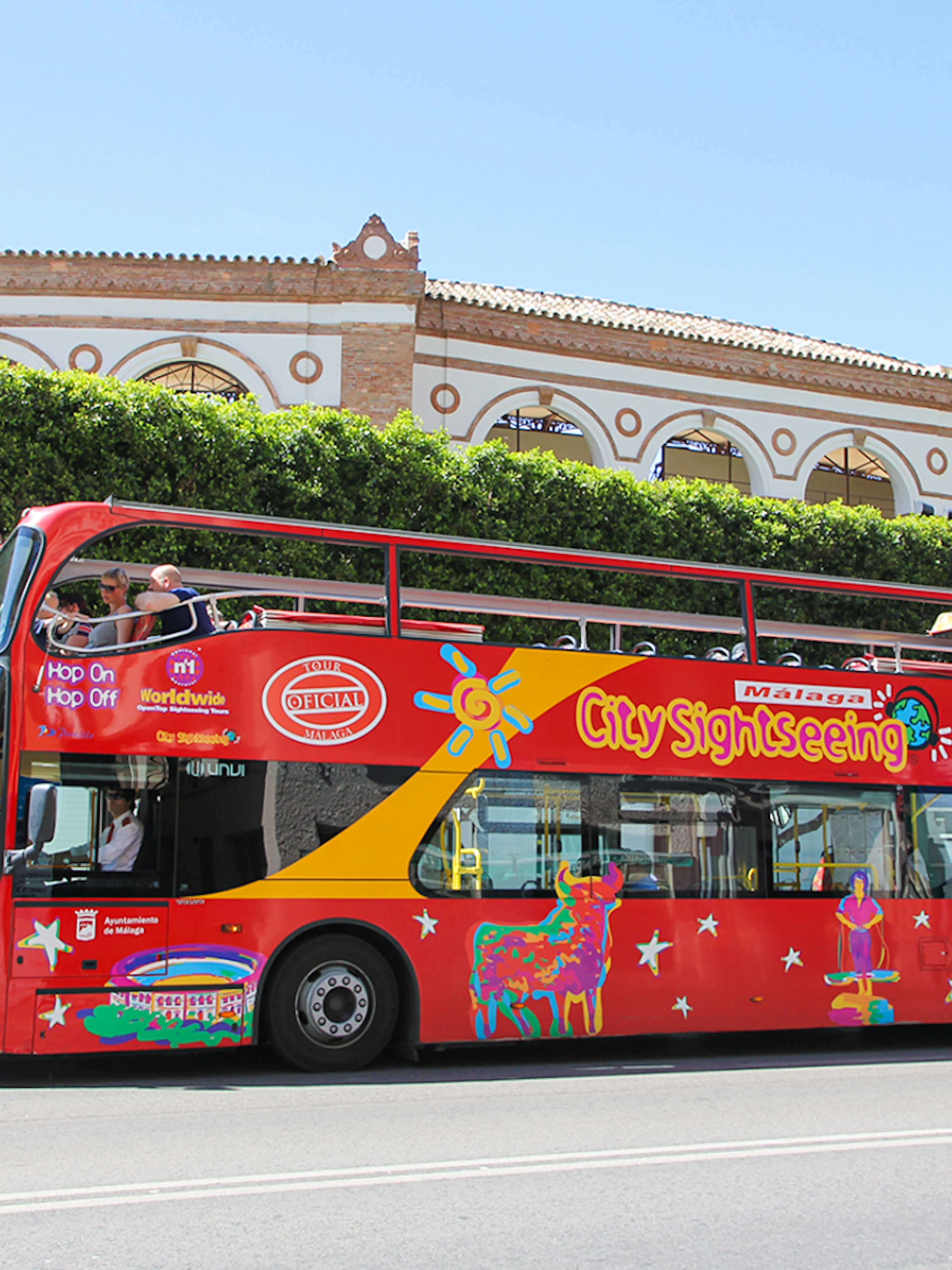 City Sightseeing HOHO bus in Malaga near historic building.