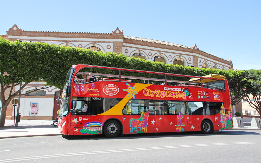 City Sightseeing HOHO bus in Malaga near historic building.