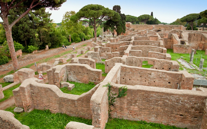 Ancient ruins of Ostia Antica with trees and pathways, Italy.