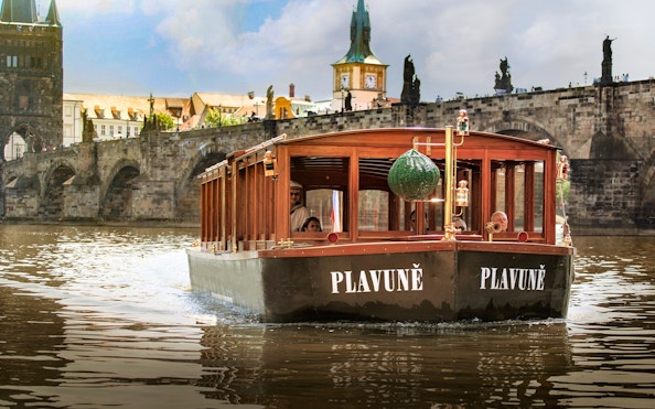 Boat cruising on the Vltava River with Charles Bridge in Prague.