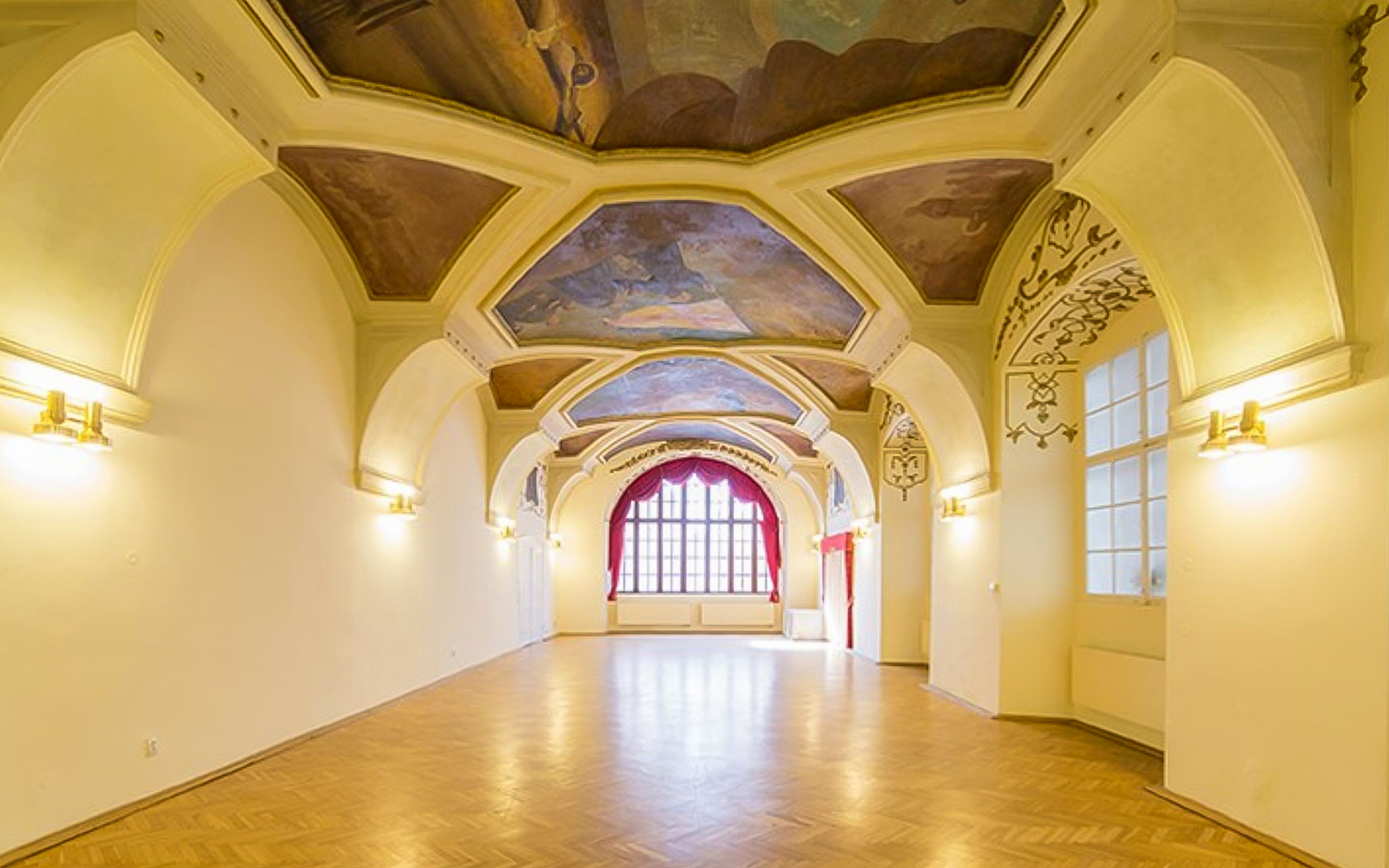 Interior of Minorite Monastery of St James in Prague with ornate ceiling and large window.