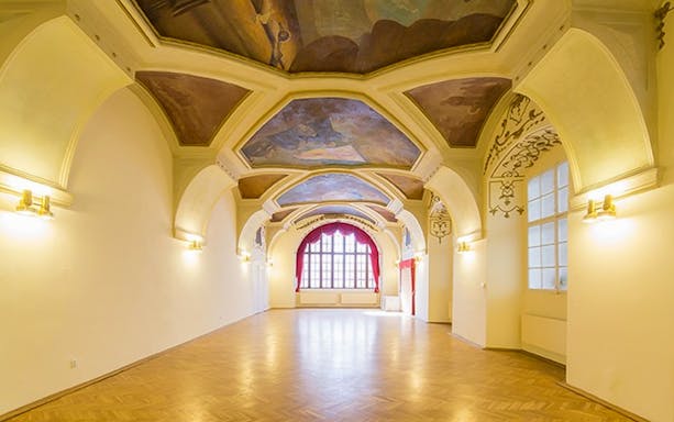 Interior of Minorite Monastery of St James in Prague with ornate ceiling and large window.