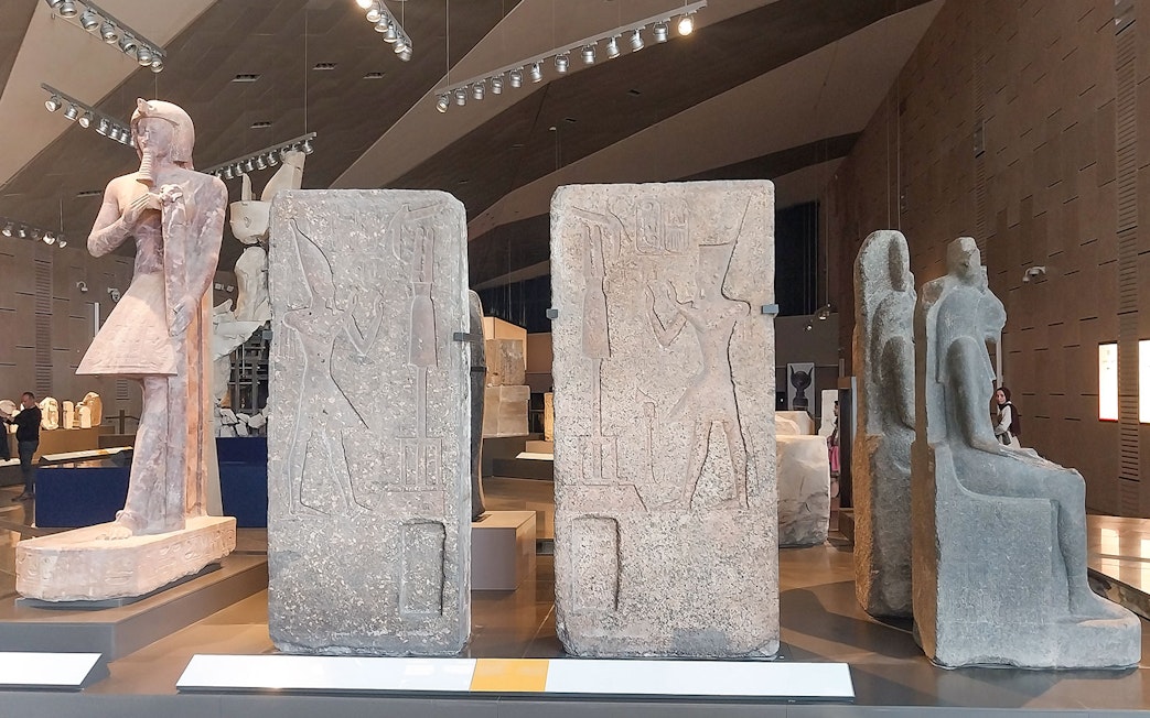 Ancient Egyptian statues and carvings inside the Grand Egyptian Museum.