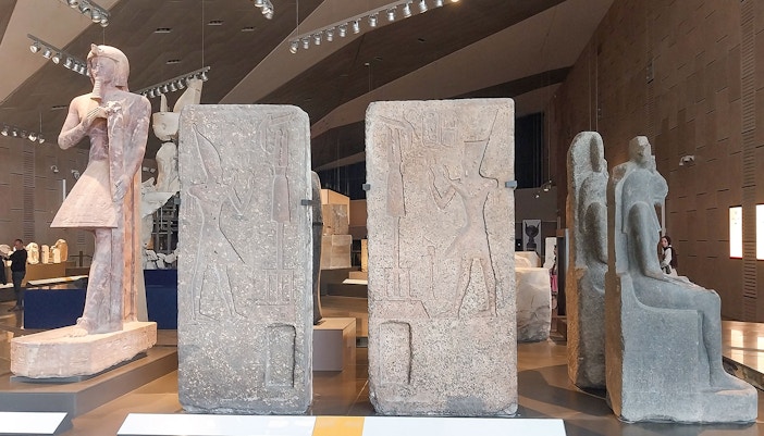 Ancient Egyptian statues and carvings inside the Grand Egyptian Museum.