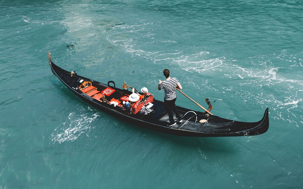 Gondola on Venice canal with passengers, part of Venice Turbopass experience.
