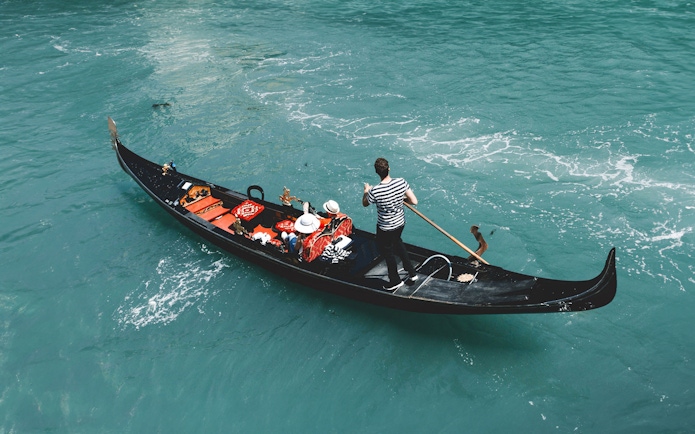 Gondola on Venice canal with passengers, part of Venice Turbopass experience.
