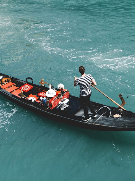 Gondola on Venice canal with passengers, part of Venice Turbopass experience.