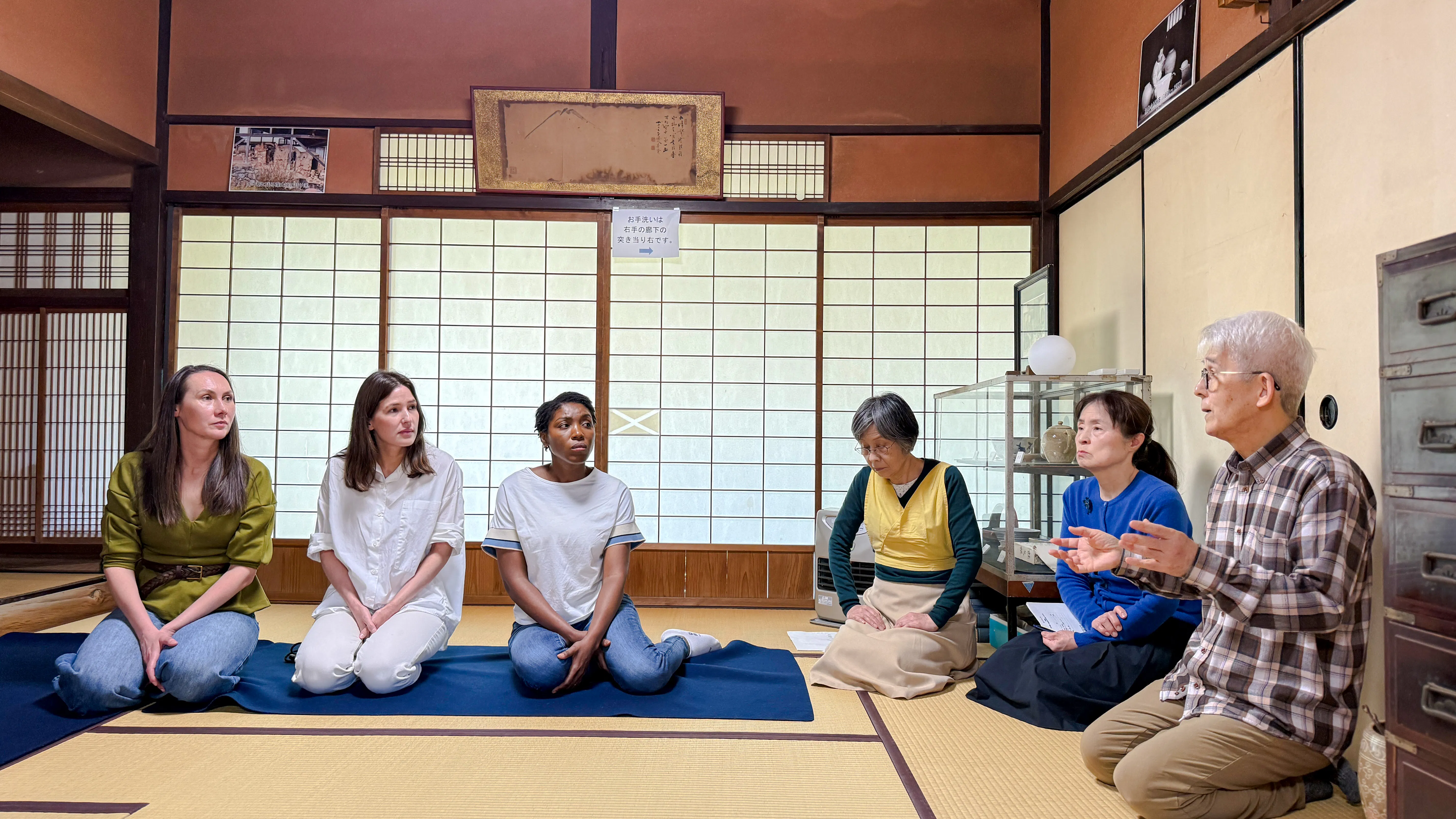 Participants in a tea ceremony at a cultural house in Hyogo, seated on tatami mats.