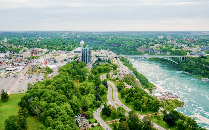 Rainbow Bridge spanning the Niagara River with Skylon Tower and lush greenery in Niagara Falls, Canada.