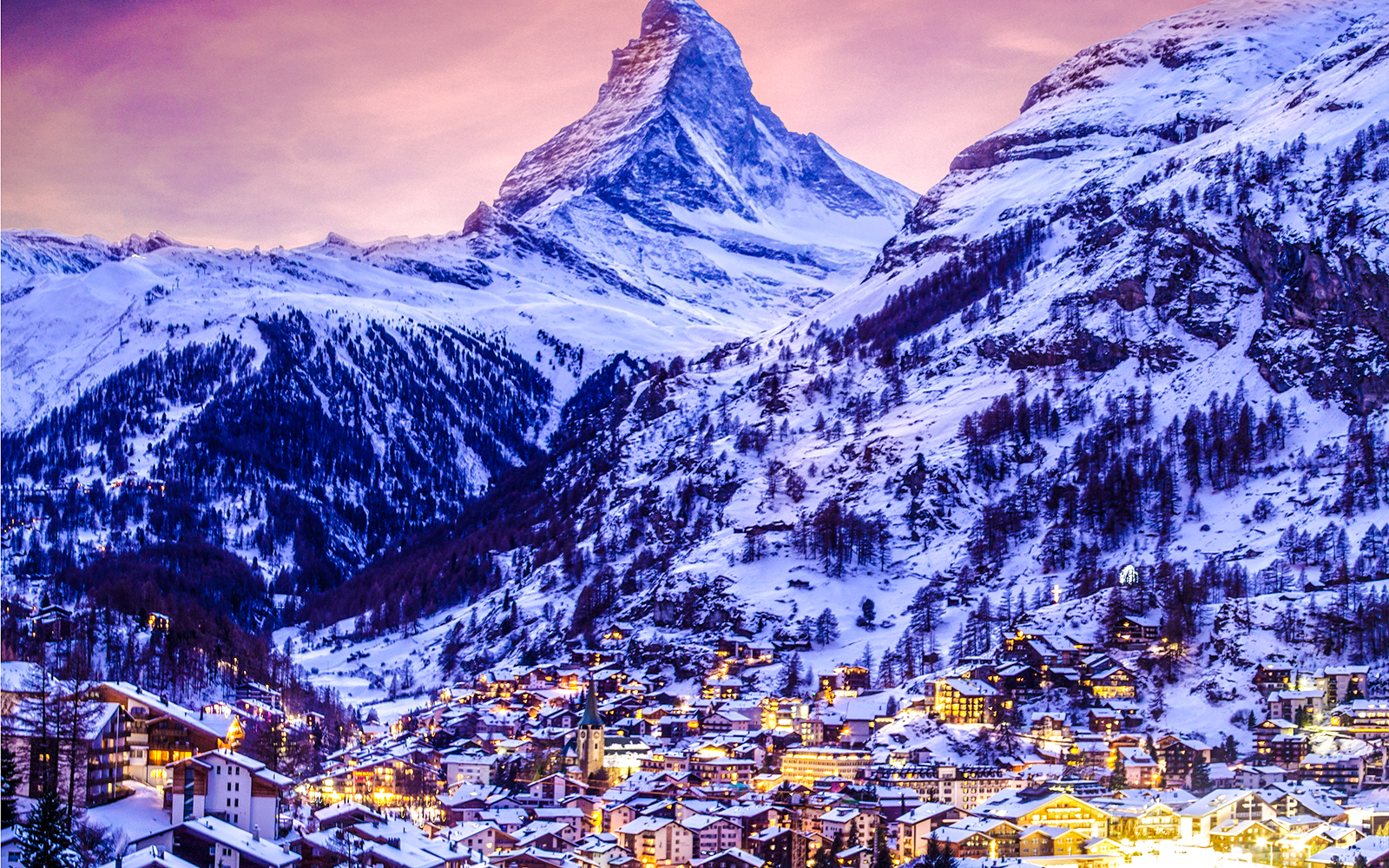 Zermatt town illuminated at twilight with the Matterhorn in the background.