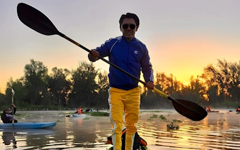 Kayaking at sunrise in Xochimilco canals with trees in the background.