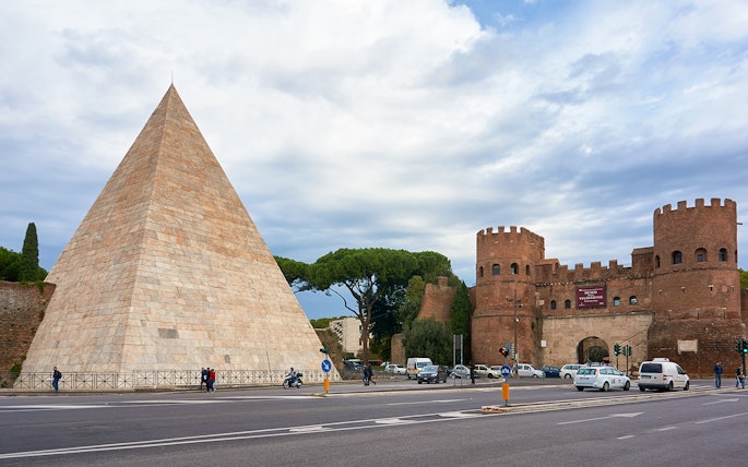 Pyramid of Caius Cestius and San Paolo Gate in Rome with passing cars.