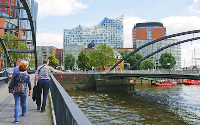 Visitors walking near Elbphilharmonie with view of Speicherstadt and HafenCity in Hamburg.