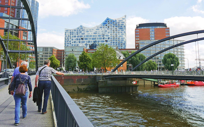Visitors walking near Elbphilharmonie with view of Speicherstadt and HafenCity in Hamburg.