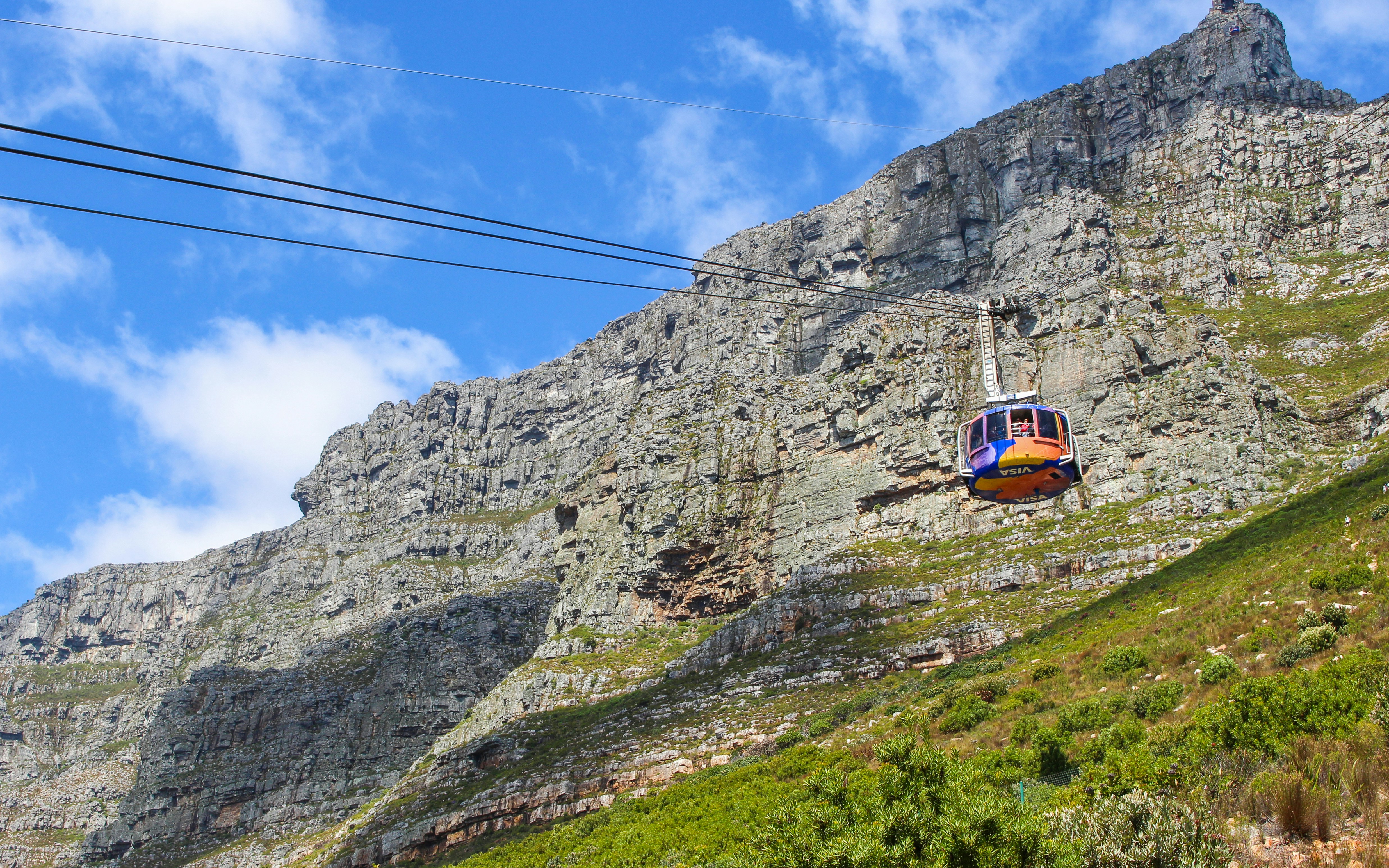 Cable car ascending Table Mountain, Cape Town, with rocky cliffs in the background.