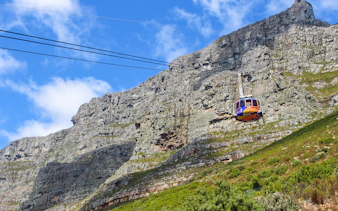 Cable car ascending Table Mountain, Cape Town, with rocky cliffs in the background.