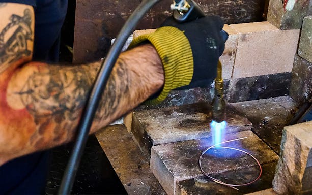 Craftsman using a torch on metal wire in Sardinian filigree workshop, Dorgali.