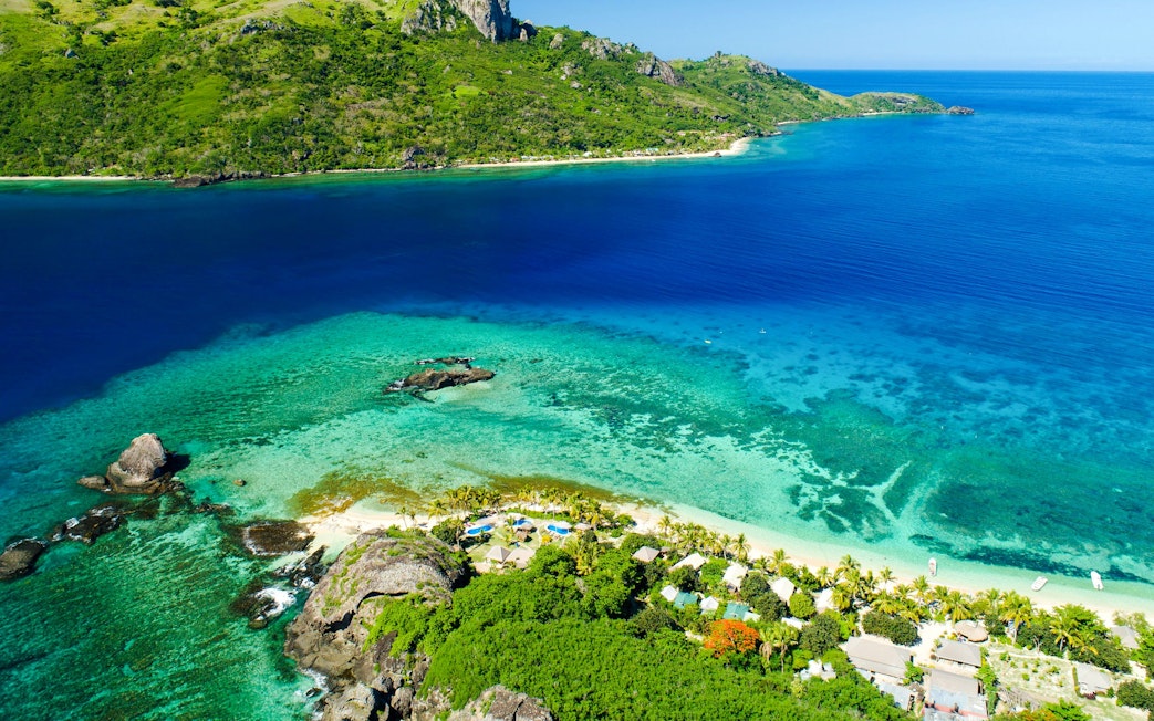 Catamaran sailing in calm blue waters near lush green islands in Fiji.
