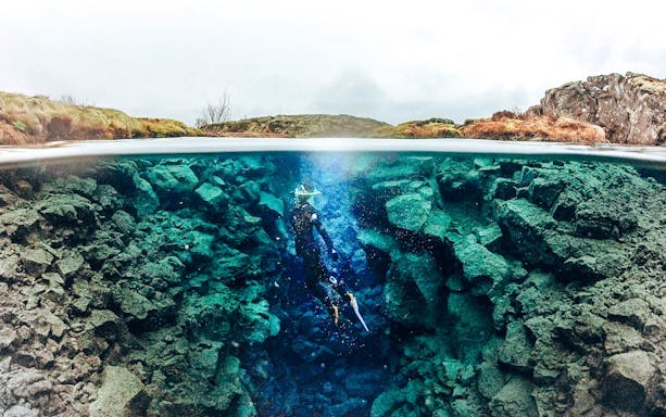 Snorkeler exploring the clear waters and rocky crevices of Silfra in Iceland.