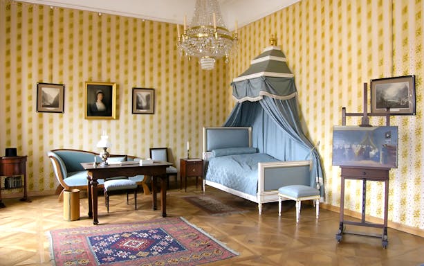 Cesky Krumlov Castle room with canopy bed, chandelier, and antique furniture.