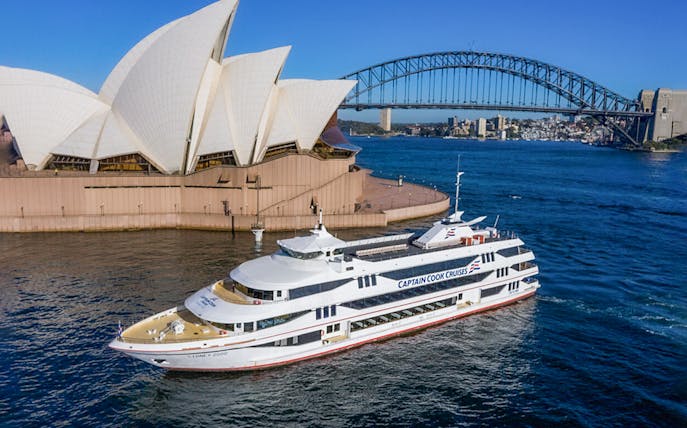 Cruise vessel near Sydney Opera House with Harbour Bridge in background.