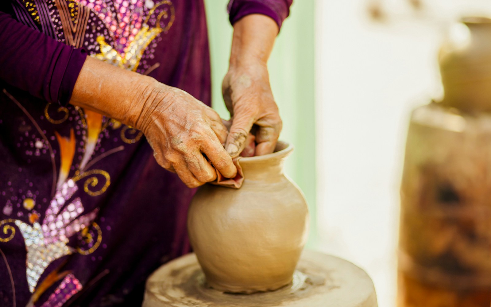 Traditional Vietnamese artisan shaping a clay pot by hand.