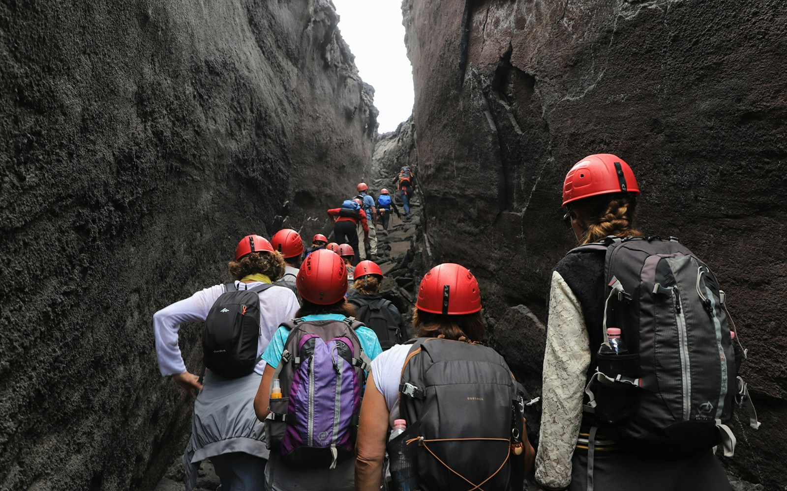 Hikers navigating narrow paths on Mount Etna during a guided tour.