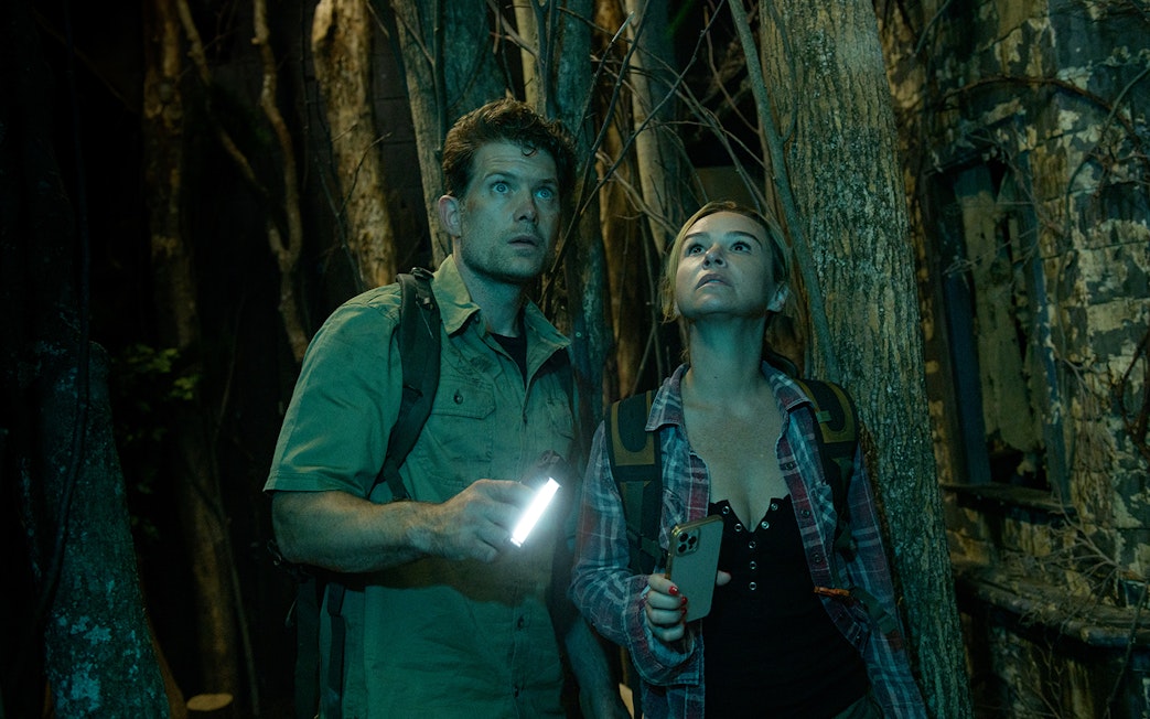Couple exploring a dark forest with flashlights, part of Go City: Las Vegas Explorer tour.