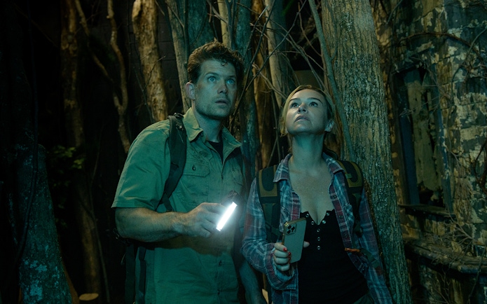 Couple exploring a dark forest with flashlights, part of Go City: Las Vegas Explorer tour.